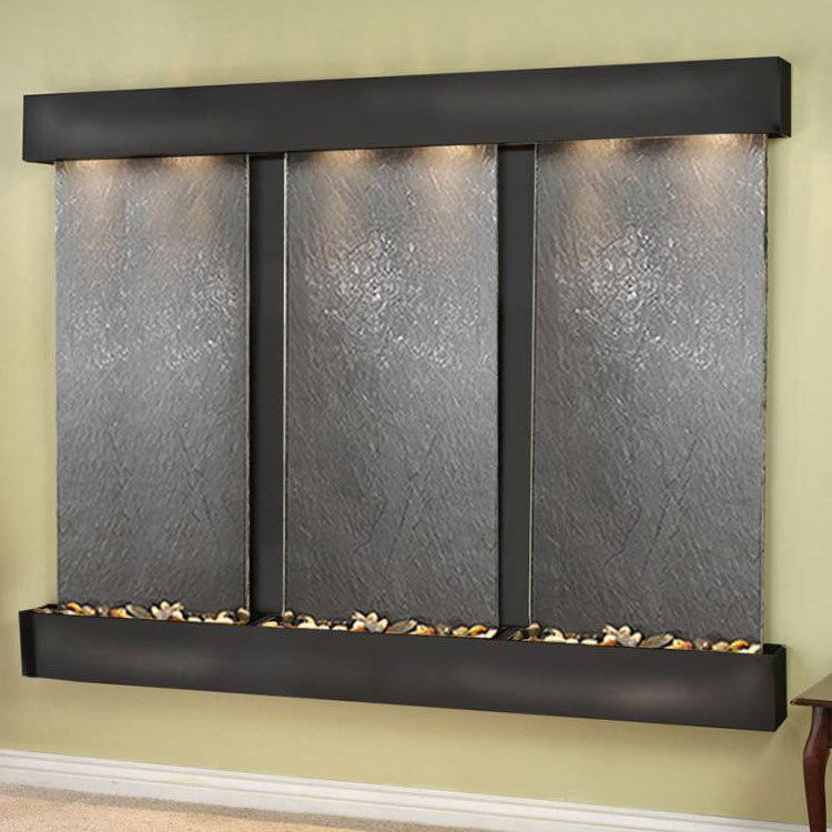 Wall-mounted water feature with three stone panels on a green wall.