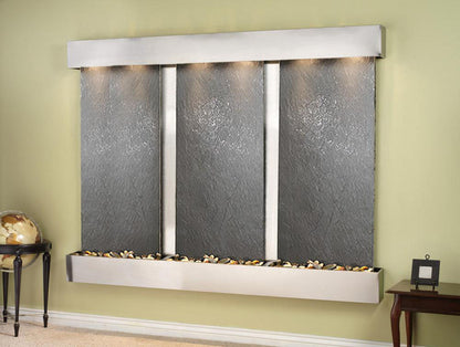 Wall-mounted water feature with four slate-like panels on a green wall.